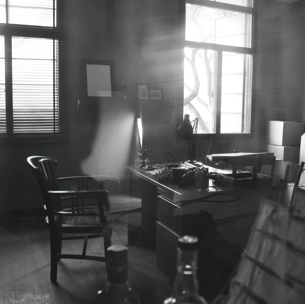 Detektivbüro mit Schreibtisch und Lichtstrahlen durch Gitterstäbe. Szene aus dem Online Escape Game 'Jagd auf den Louvre-Dieb' von i-Detect.